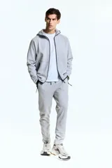 Campera deportiva gris con capucha, cierre frontal y bolsillos laterales con cierre. Confeccionada en tejido funcional DryMove™ que ayuda a absorber el sudor.