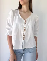 Camisa blanca de mangas 3/4 con detalle de volados en los puños y botones de madera.