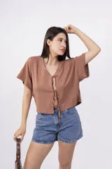 Remera color amarillo pálido de corte holgado, escote en V con lazo y mangas cortas.