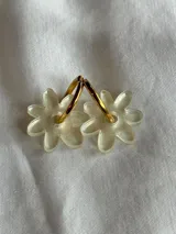Aros colgantes plateados con dije de flor acrílica color dorado.