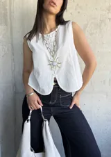 Chaleco blanco con botones al frente y corte irregular en el ruedo.