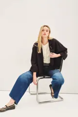 Saco de lino color negro, de corte amplio, con solapa, bolsillos falsos y pin de guitarra en la solapa.