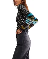 Top de manga larga ajustado, color negro con estampado floral pequeño en tonos beige y amarillo. Presenta cuello alto tipo mock con borde festoneado y puños alargados de punto con diseño multicolor a rayas y patrones geométricos en tonos azul, verde, marrón y negro.