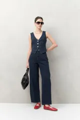 Pantalón de jean azul oscuro, de tiro alto y corte amplio con pinzas centrales.