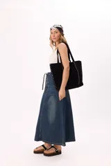 Bolso negro tipo tote bag de gamuza sintética con tachas metálicas plateadas en los laterales.