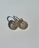 Aros dorados con forma circular, con centro de resina blanca y borde de strass.