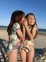 Traje de baño enterizo de niña, con estampado de hojas y círculos, manga corta y moño en la espalda.