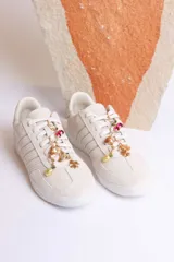 Zapatillas bajas de gamuza celeste con cordones y pañuelos estampados atados a los cordones.