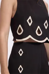 Conjunto de top crop y pantalón palazzo negros con bordados calados en forma de rombos con borde festoneado en color crudo.