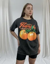 Remerón negro con efecto gastado y estampado de naranjas y texto en color naranja.