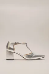 Sandalia de cuero color plateado con diseño en punta, taco recto de 5 cm y tira en T con hebilla ajustable al tobillo.