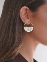 Par de aros dorados con forma circular, divididos horizontalmente: la mitad superior es un aro fino y la mitad inferior es un semicírculo sólido.