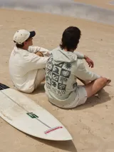 Buzo con capucha color verde claro, con estampado de motivos playeros en la espalda y texto "Rainbow Bay The Goldcoast GEM".