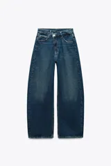 Pantalón de jean azul oscuro, corte ancho, tiro medio, con cintura cruzada y cierre asimétrico con cremallera y botón.
