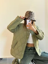 Campera verde militar con diseño capitoneado, cuello redondo y cierre frontal con botones a presión.