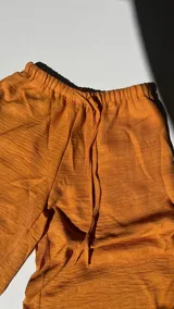 Pantalón palazzo color naranja, de tiro alto con cintura elastizada y cordón ajustable.