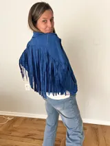 Campera de gamuza sintética color azul con flecos largos en mangas y espalda, corte recto con solapas clásicas.