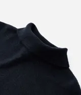 Vestido corto negro de punto ligero, con cuello alto y mangas largas.