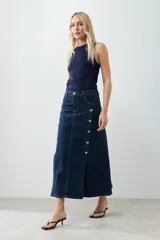 Maxi falda de jean azul oscuro, con tajos y botones dorados.