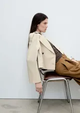 Chaqueta corta color beige con doble botonadura, cuello con solapa y bolsillos laterales.