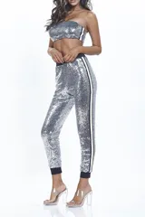 Conjunto plateado de lentejuelas, compuesto por un top bandeau y un pantalón tipo jogging con cintura y puños negros.