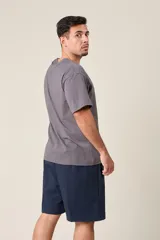 Bermuda deportiva gris de nylon, de corte suelto, con cintura elástica y cordón de ajuste. Cuenta con detalles de líneas negras en los costados y bolsillos laterales con cierre.