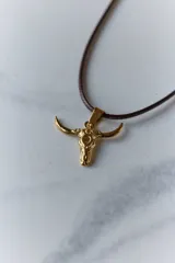 Dije plateado con forma de cráneo de toro con orificio en la frente.