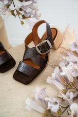 Sandalias de cuero con diseño cruzado y tacón bajo, color marrón con textura tipo cocodrilo.