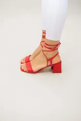 Sandalias rojas de cuero con tiras finas para atar al tobillo y tacón cuadrado.