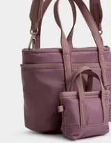Cartera tipo tote color beige, de tela deportiva, con doble asa corta y correa larga regulable y desmontable. Tiene un bolsillo lateral con forma de pouch.