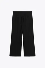 Pantalón negro de tiro medio con trabillas en la cintura, pernera recta y corte cropped. Cierre frontal con cremallera y ganchos metálicos.