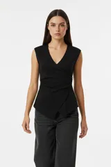 Top negro sin mangas, con escote en V cruzado y detalle de botones laterales. Presenta un corte ajustado al cuerpo con un diseño asimétrico en el ruedo.