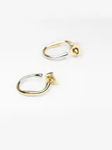 Aros metálicos con diseño bicolor en acabado dorado y plateado, de forma circular abierta y cierre de broche.