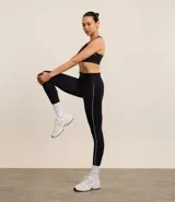 Calza deportiva negra confeccionada en microfibra, con cintura texturizada y ribete blanco contrastante a lo largo de la pierna.