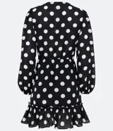 Vestido corto negro con lunares blancos, escote en pico, mangas largas abullonadas, cintura entallada y volados en el bajo.
