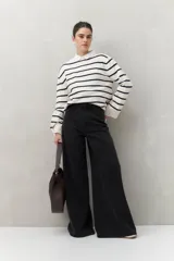 Pantalón de jean negro de calce ultra wide leg, tiro alto y silueta amplia desde la cadera hasta el bajo. Diseño clásico de cinco bolsillos y cierre con botón metálico y cremallera.