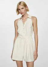 Mono corto color crema, sin mangas, con cuello camisero, cierre frontal con botones y cinturón ajustable.