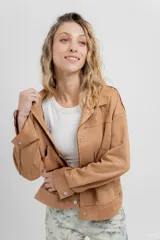 Chaqueta color camel, corte camisa de gamuza con elastano, corte recto abotonado en el frente con botones metálicos y bolsillos grandes en el frente.