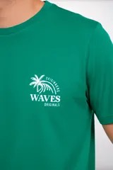 Remera de manga corta color verde esmeralda, con cuello redondo. Presenta un pequeño estampado en el pecho con un diseño de palmera y olas y el texto "WAVES MIAMI".