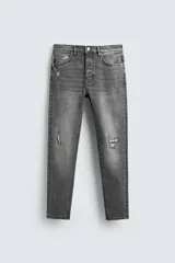 Pantalón de jean azul oscuro con efecto lavado y roturas en las rodillas, de corte ajustado al cuerpo desde la cintura hasta el tobillo.