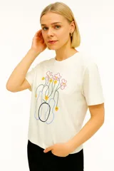 Remera color crema de algodón con estampado de flores abstractas en tonos rosa, amarillo, azul y negro.