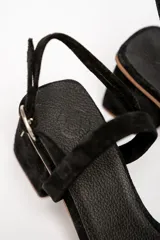 Sandalias negras de cuero gamuzado, con tira fina sobre los dedos y tobillo, y taco cuadrado bajo.