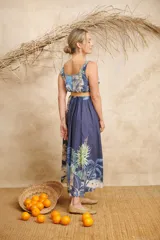 Vestido midi azul con estampado de palmeras y otros motivos tropicales, escote redondo y cinto de rafia.