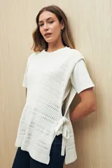 Chaleco blanco de algodón tejido con punto calado y lazos laterales.