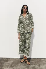 Camisa verde militar con bordado floral blanco, cuello solapa, escote en pico, manga tres cuartos con detalle de guipur y cierre frontal con botones.