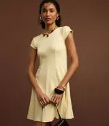 Vestido negro de punto Roma, corto, con escote redondo y mangas cortas. Presenta recortes en el talle que definen la silueta ajustada en el torso y falda acampanada.