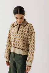 Sweater de punto color beige con diseño de rombos marrones, cuello polo con botones y mangas largas abullonadas.
