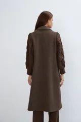 Tapado largo y recto color marrón con mangas tejidas con diseño de trenzas. Tiene cuello solapa, cierre frontal con botones ocultos y bolsillos con solapa. Con forro.