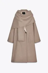 Abrigo largo color beige confeccionado en lana. Presenta cuello solapa con bufanda desmontable, manga larga, bolsillos laterales y cierre frontal cruzado con botones.
