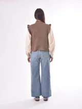 Chaleco tejido color beige con cuello alto y volados en los hombros. Diseño con patrón de rombos en relieve.